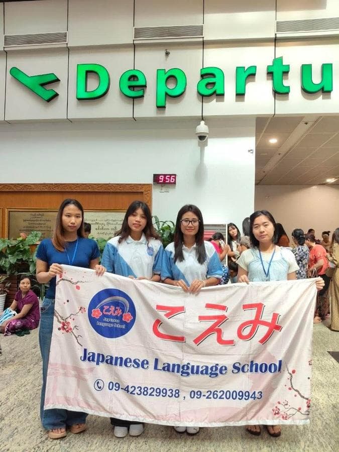 Four students holding the school banner under the departure sign