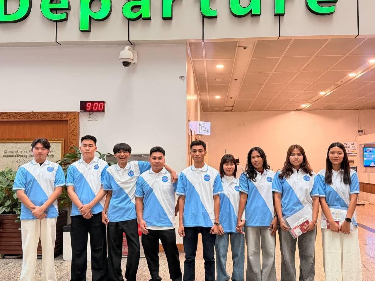 Group photo with the school banner at the departure hall