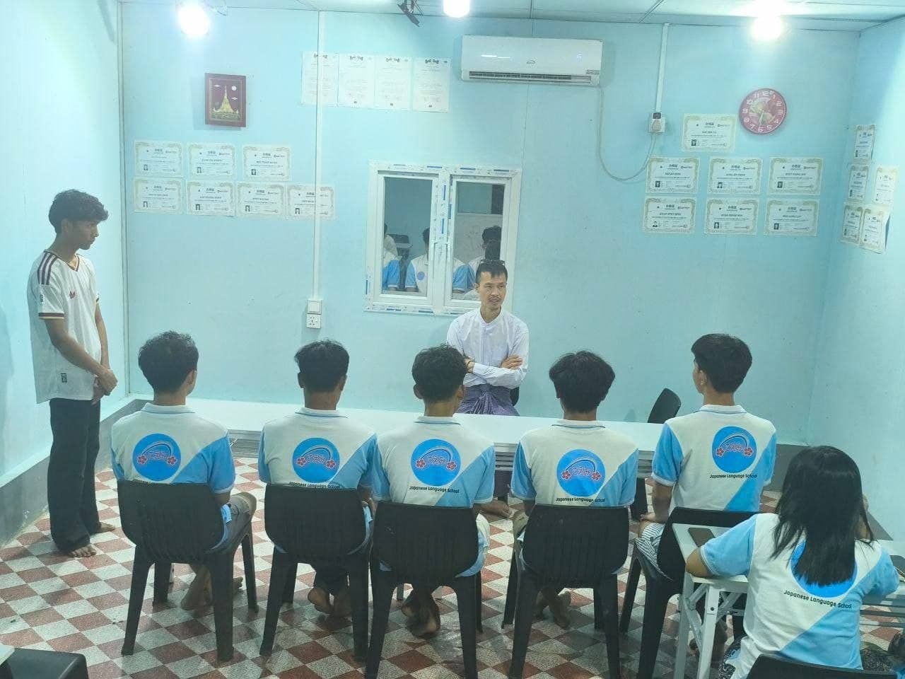 Students seated facing their Japanese teacher in a classroom